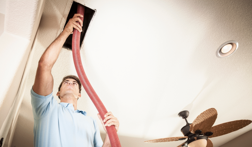 Guy cleaning air duct with a vacuum cleaner
